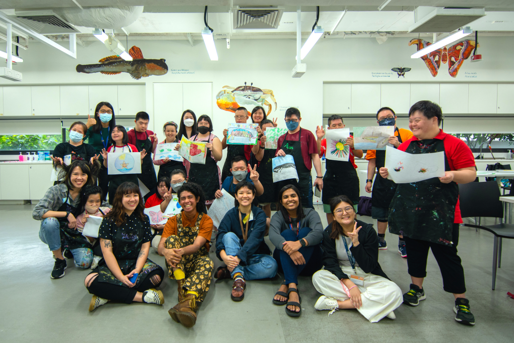 Participants looking happy while holding up their artworks in an art class.